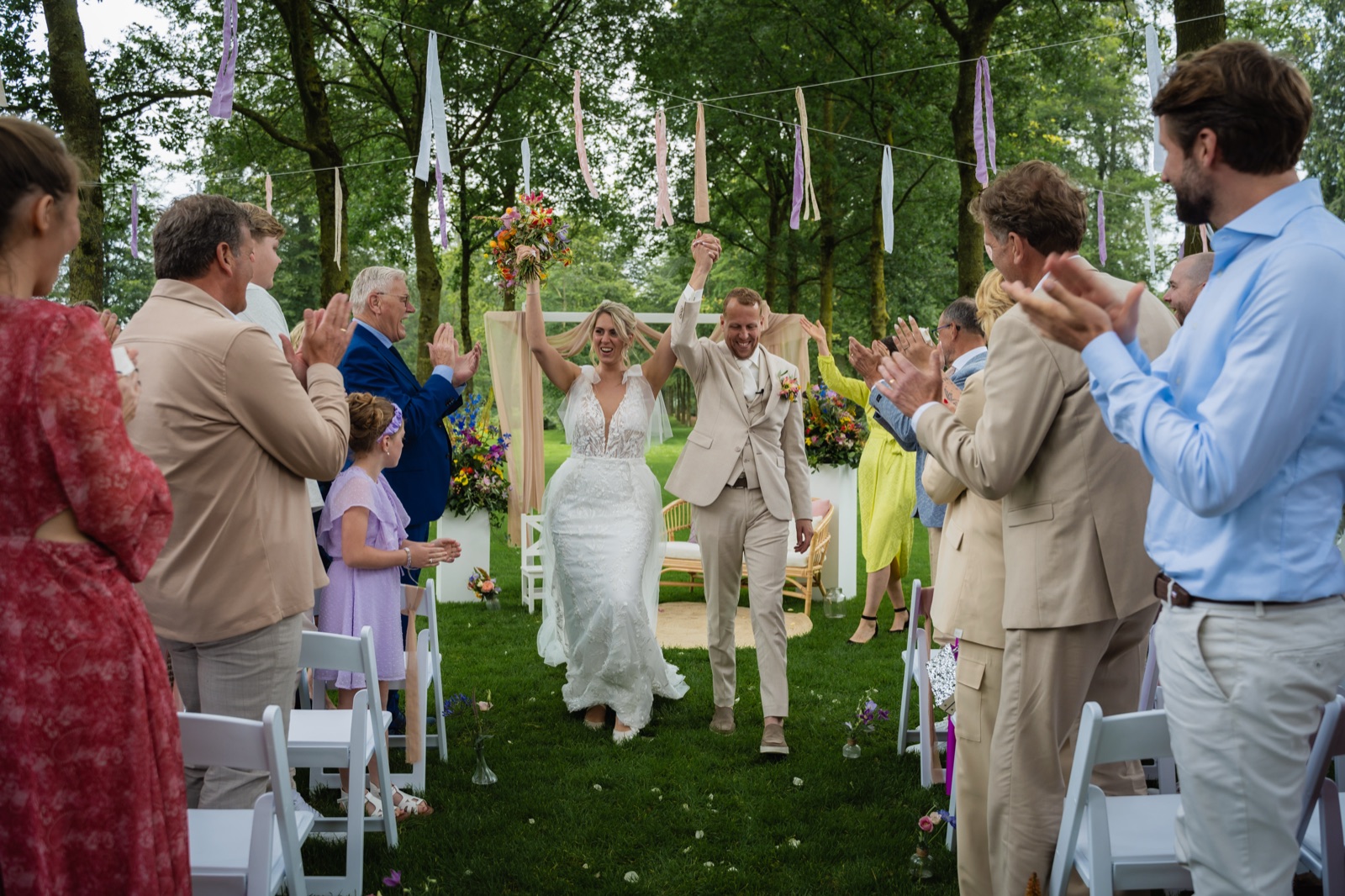 Bruidspaar tussen juichende gasten tijdens ceremonie — documentaire trouwfotografie